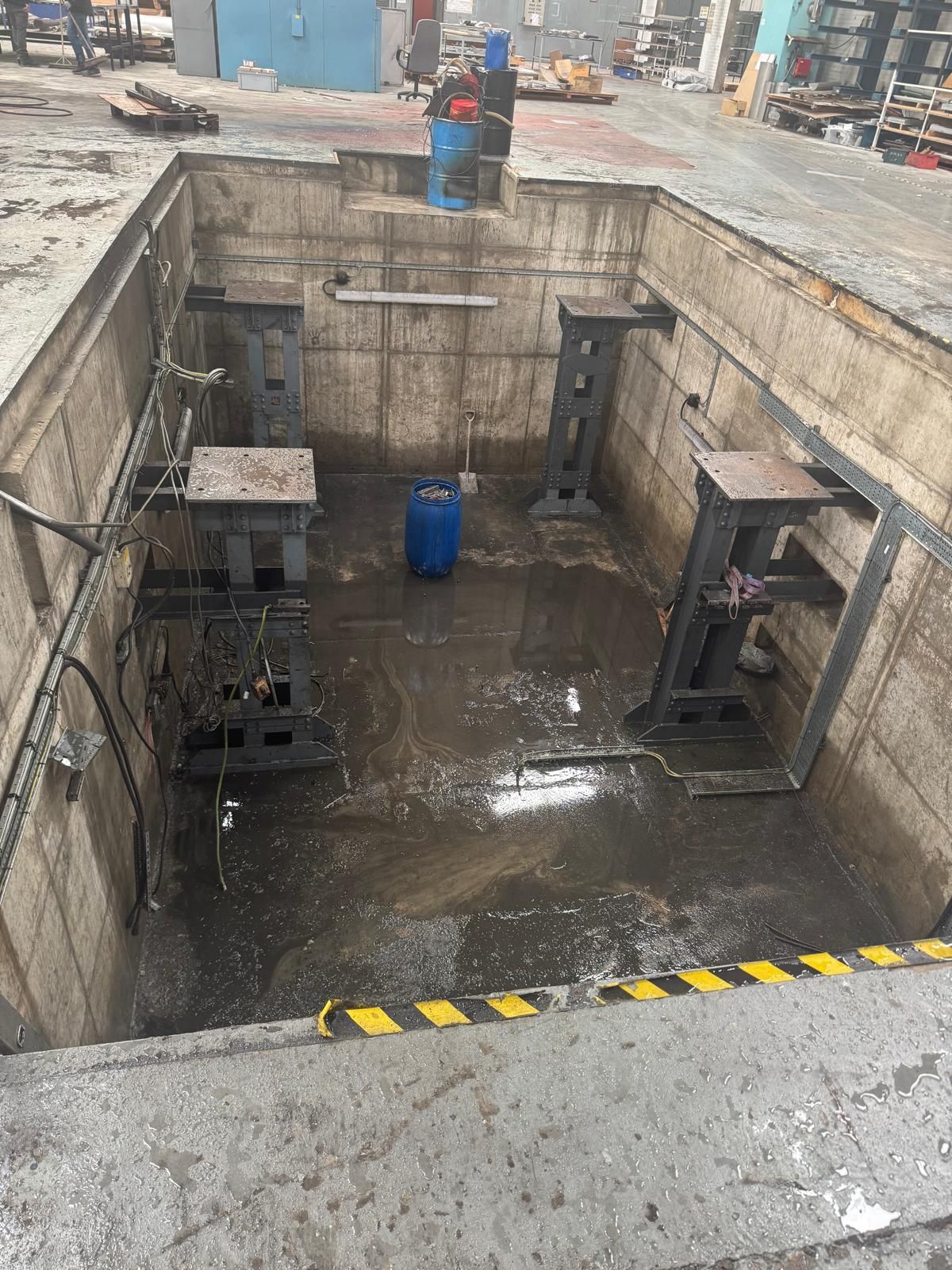 A drained industrial process pit inside a factory, part-way through a tank cleaning and decontamination project.
